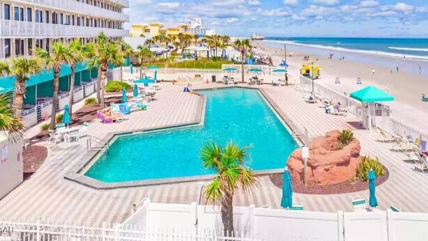 Een resort met een groot zwembad, toegang tot het strand en uitzicht op de oceaan.