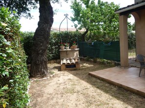 Ein Garten mit einer Steinsitzbank, einer Pergola und einem grünen Zaun.