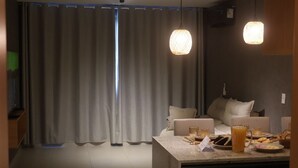 A modern kitchen with a dining area, featuring a large window, curtains, and pendant lighting. - MHV Milagres - Manah B 212 &  B 211  (São Miguel dos Milagres)