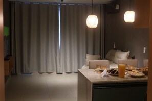 A modern kitchen with a dining area, featuring a large window, curtains, and pendant lighting. - MHV Milagres - Manah B 212 &  B 211  (São Miguel dos Milagres)