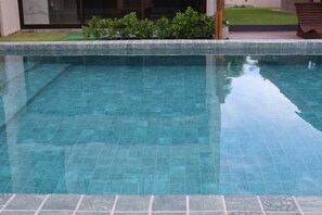 A clear swimming pool with a tiled edge, surrounded by a grassy area and a bench. - MHV Milagres - Manah B 212 &  B 211  (São Miguel dos Milagres)