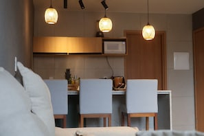 A modern kitchen with pendant lighting, a microwave, and a dining area with chairs. - MHV Milagres - Manah B 212 & B 211 (São Miguel dos Milagres)