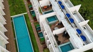 Un hotel con diverse piscine, aree salotto all'aperto e un prato curato.