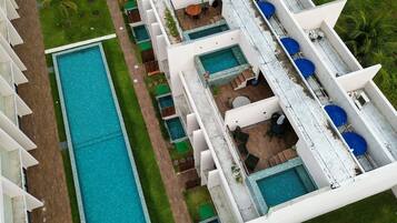 Um hotel com várias piscinas, áreas de estar ao ar livre e um gramado bem cuidado.