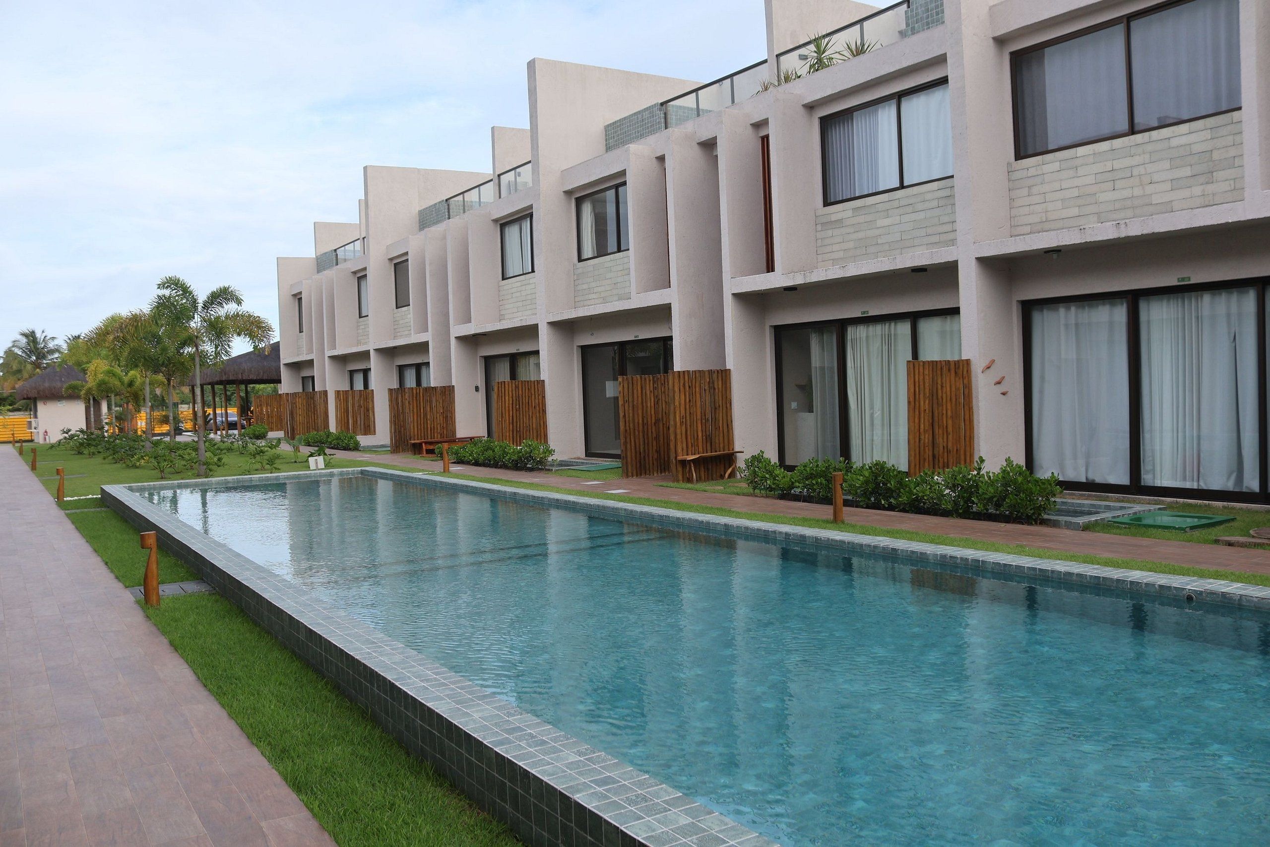 A modern hotel with a swimming pool, multiple balconies, and a well-maintained garden area.