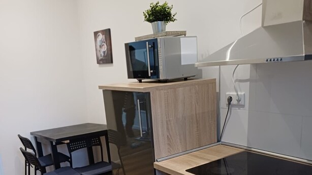 Une cuisine compacte équipée d’un four à micro-ondes, d’un four traditionnel et d’une petite table à manger avec des chaises.