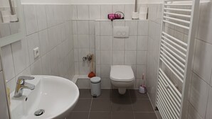 Une petite salle de bain propre, avec un lavabo blanc, des toilettes et un porte-serviettes.