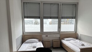 A small, modern room with two single beds, a round table, and a chair. - Haus an der Brücke (Munich)