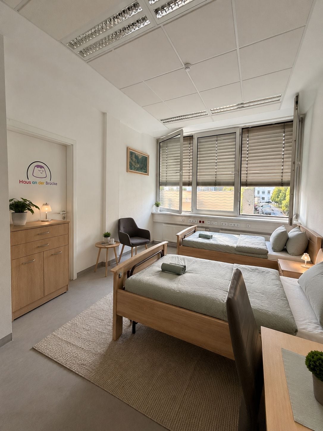 Un dormitorio moderno con dos camas, un escritorio, una silla, un aparador y una ventana con persianas.