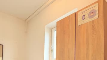 A bedroom with a bed, a wooden wardrobe, a window, and a radiator.