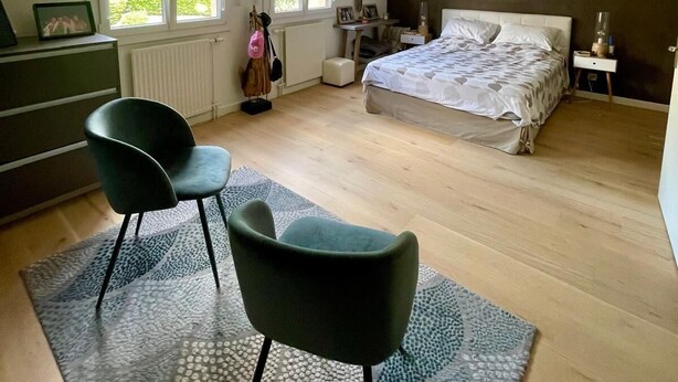 Un dormitorio con cama, dos sillas, tocador, escritorio y ventana.
