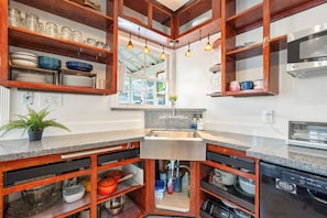 A kitchen with wooden shelves, a granite countertop, a stainless steel sink, and a dishwasher. - Nautical Pirate Home Near Park & Trails | 3BR South SF (South San Francisco)
