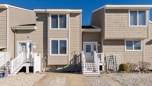 A row of two-story townhouses with a central entrance, a small porch, and a gravel driveway. - Beautifully Updated Diamond Beach Townhouse (Wildwood)