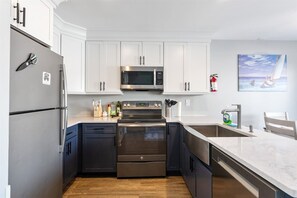 A modern kitchen with stainless steel appliances, white cabinetry, and a marble countertop. - Beautifully Updated Diamond Beach Townhouse (Wildwood)