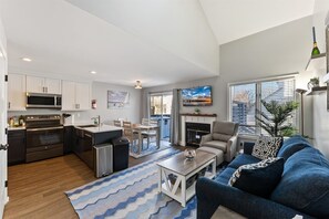 A modern kitchen with built-in appliances, a dining area with a table and chairs, a living room with a sofa and a coffee table, and a fireplace. - Beautifully Updated Diamond Beach Townhouse (Wildwood)
