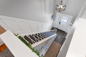 A staircase with a white railing, a hanging light fixture, and a door with a window. - Beautifully Updated Diamond Beach Townhouse (Wildwood)
