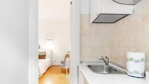 Una cocina moderna con un lavamanos, un dispensador de papel higiénico y una cama en la habitación contigua.