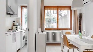 Una cocina funcional con lavadora, refrigerador pequeño y zona de comedor con mesa y sillas.