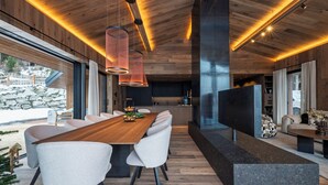 Un intérieur moderne avec une table à manger en bois, des chaises blanches et des luminaires suspendus.