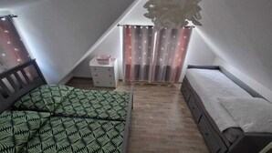 A small, triangular attic bedroom with a bed, a nightstand, and a bench.