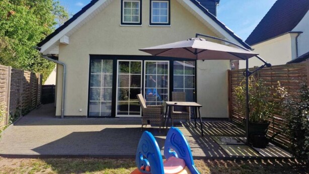 A house with a patio, a slide, and a table with chairs.