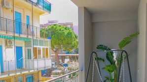 A balcony with a white swing chair and a potted plant. - Cozy Beach House (Cefalù)