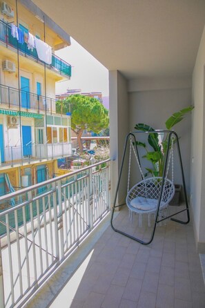 A balcony with a white swing chair and a potted plant. - Cozy Beach House (Cefalù)