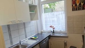 Et køkken med vindue, radiator og skraldespand.