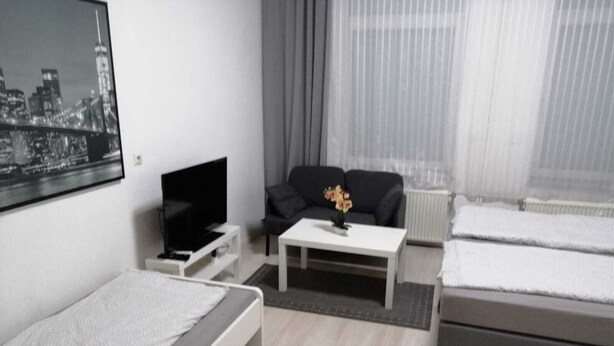 Et moderne hotelværelse med seng, sofa, fjernsyn og sofabord.