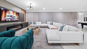 A modern living room with a flat-screen TV, a fireplace, a sectional sofa, and a pool table. - 9BR house sleeps 20 with spa in kissimmee (Kissimmee)
