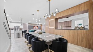 A modern kitchen with a central island, black bar stools, and pendant lighting. - 9BR house sleeps 20 with spa in kissimmee (Kissimmee)