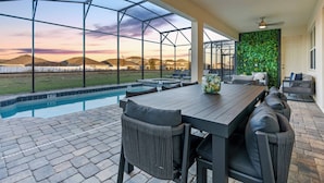 A covered outdoor area with a pool, a dining table, and chairs. - 9BR house sleeps 20 with spa in kissimmee (Kissimmee)
