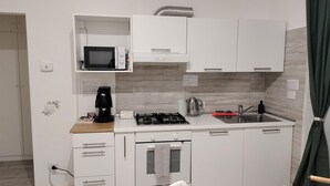 Eine kleine Küchenzeile mit Mikrowelle, Kaffeemaschine, Gasherd und Spüle.