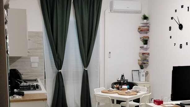 Ein modernes, helles Schlafzimmer mit Bett, Nachttisch und einer kleinen Schreibtischzeile mit Stuhl.