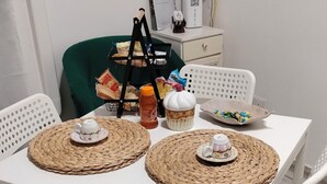 Ein Esstisch mit gewebten Tischsets, weißen Stühlen und einer kleinen Pflanze auf einem Regal.