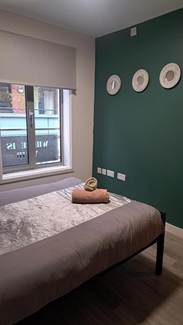 A bedroom with a bed, a window, and a green wall with three circular wall decorations. - Central Sheffield 1-Bed | Walk to Shops & Dining (Sheffield)