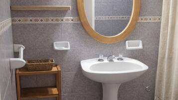 A bathroom with a pedestal sink, a round mirror, and a shower curtain.