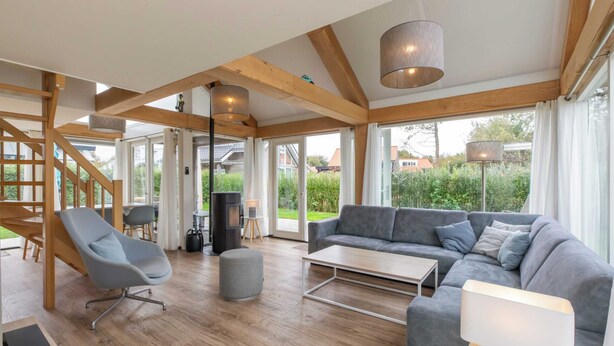 A spacious living area with a wooden ceiling, a grey sofa, a grey armchair, and a coffee table. - 6-person Holiday Home in Renesse (Renesse)