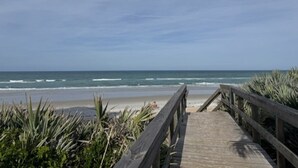 Une promenade en bois qui mène à une plage offrant une vue sur l’océan.