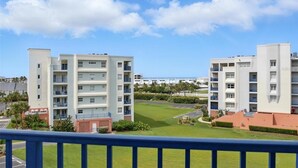 Un hôtel moderne à plusieurs étages, doté de balcons, d’une pelouse bien entretenue et offrant une vue dégagée sur l’océan.