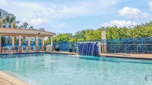 Une piscine agrémentée d’un élément décoratif aquatique, de chaises longues et d’un espace abrité.