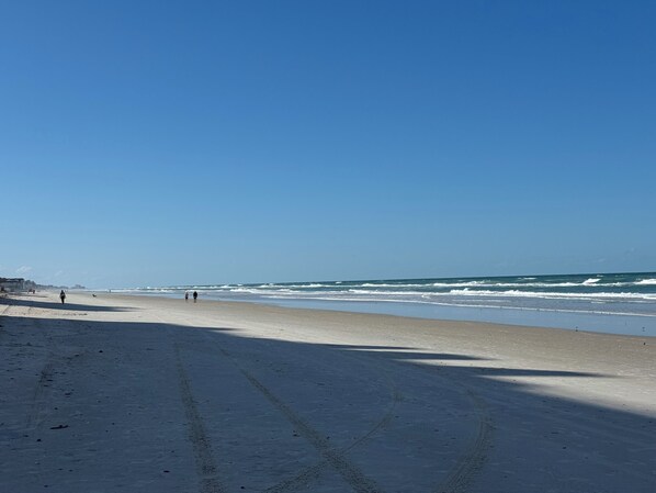 A beach with a clear sky, sandy shore, and ocean waves.