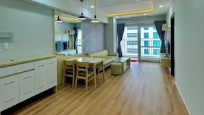 Un soggiorno moderno con zona pranzo, parquet e ampie finestre che offrono vista sulla città.