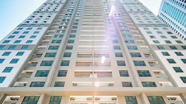 Un edificio alto con un cartello blu che riporta la scritta "TOA NHAO C3" e un cartello più piccolo con "Pham Van Dong".