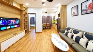 Un soggiorno moderno con una televisione a schermo piatto, una ventola a soffitto, un divano e un'area pranzo con tavolo e sedie.