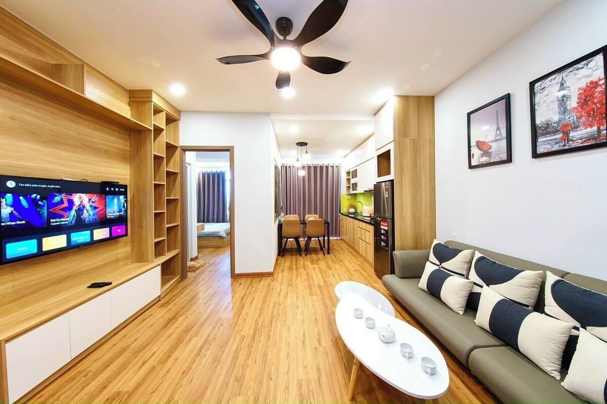 A modern living room with a flat-screen TV, a ceiling fan, a sofa, and a coffee table.