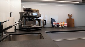 A modern kitchen with a built-in coffee machine, a stainless steel sink, and a wooden cutting board.