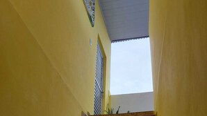 A staircase with wooden steps leading upwards, flanked by yellow walls, and a window at the top. - House, 2 bedrooms with air conditioning, airy, fully equipped. (Salvador)