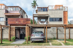 Un edificio moderno con entrada de madera, un coche estacionado adelante y un letrero que dice 'Lani Beach Villas'.