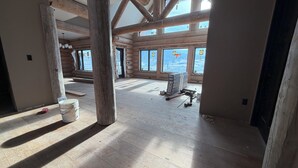 Ein geräumiges Zimmer mit Holzbalken, großen Fenstern und einer hohen Decke.